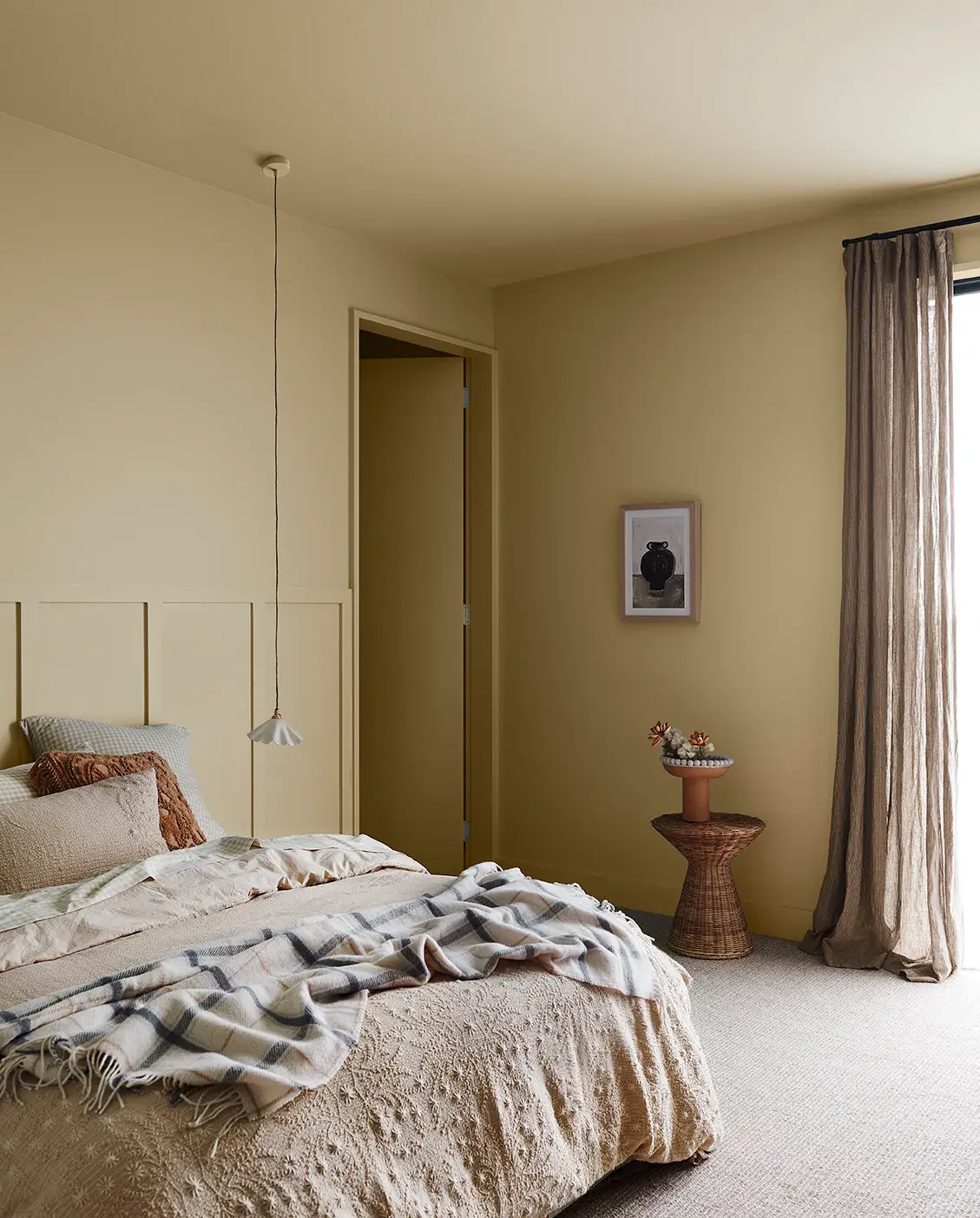 Bedroom with warm beige walls and ceiling and neutral curtains
