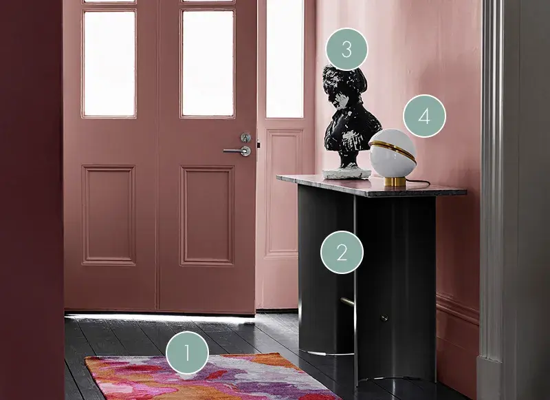 A black statue on a table in a pink painted hallway