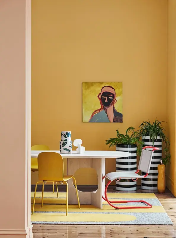 A white dining table in front of a yellow-walled backdrop