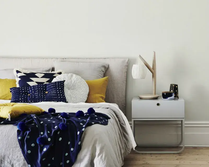 Bedroom with double bed featuring blue, mustard and linen covers. 