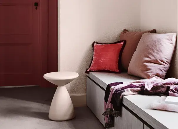 view of cream and purple reading nook with side table and velvet cushions