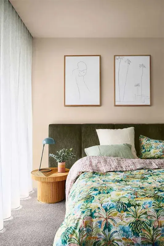 Bedroom with neutral walls, green headboard and timber side table.
