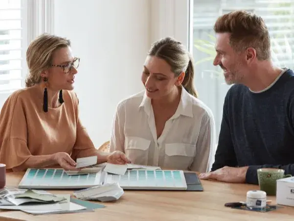 A man and a woman sitting at a table with a Dulux Colour Atlas, talking to a colour designer