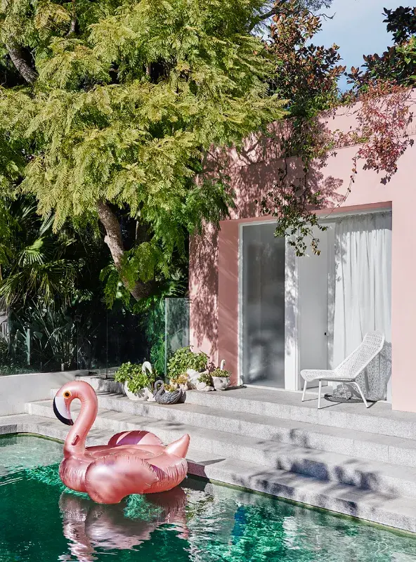 Pink pool house with inflatable flamingo in pool.
