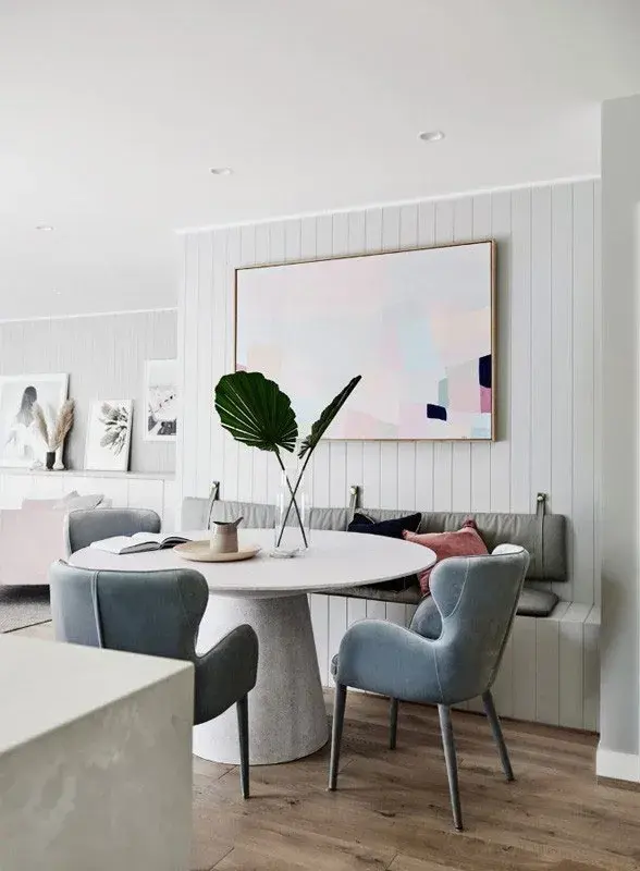 Dining room with chairs around a stone table. There is a vase with two decorative large leaves in it.