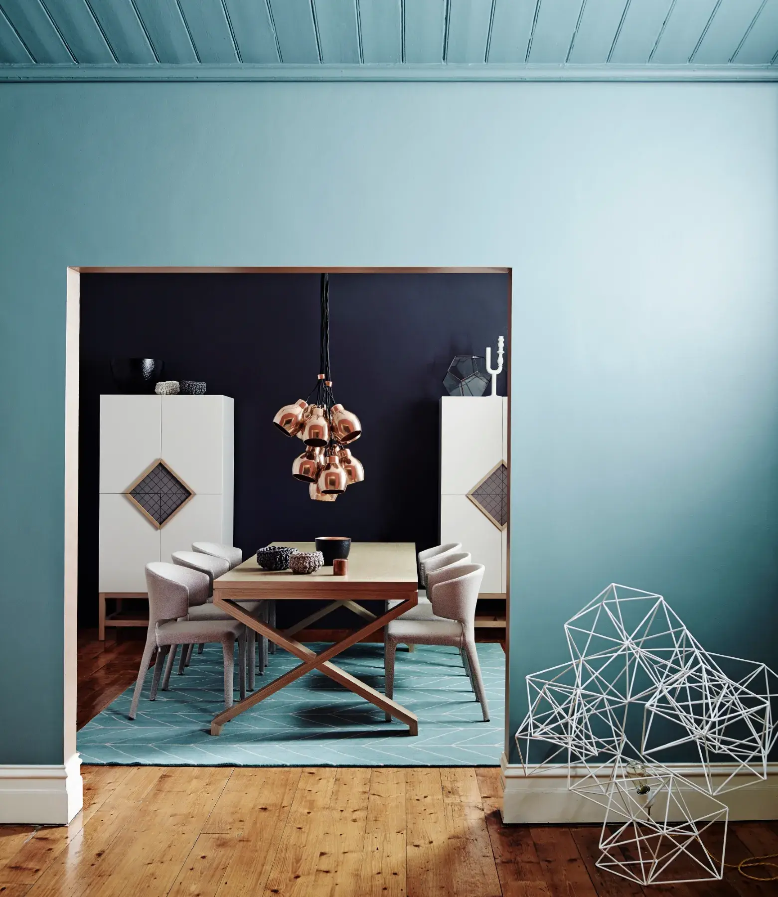 Contrasting light orange and earthy hues with deep blue dining room with white accents and timber flooring.