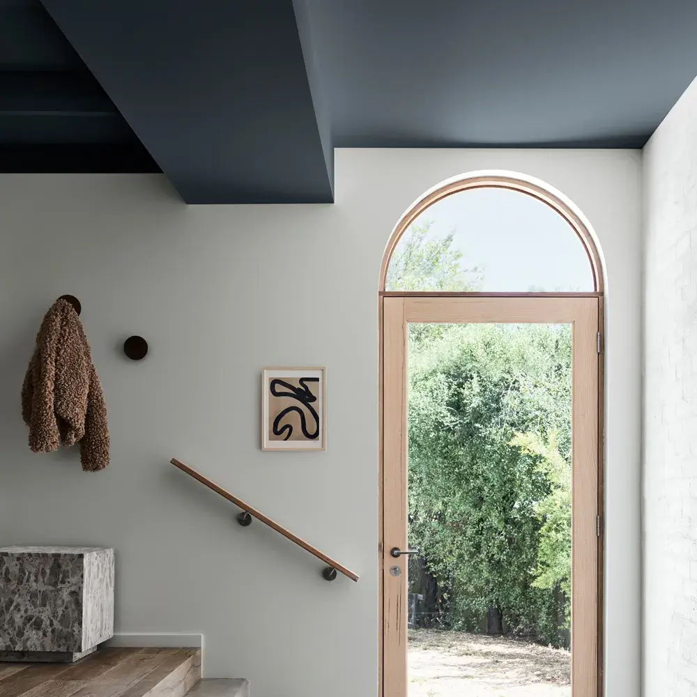 Light-filled entrance to living area with glass door and railing up stairs.