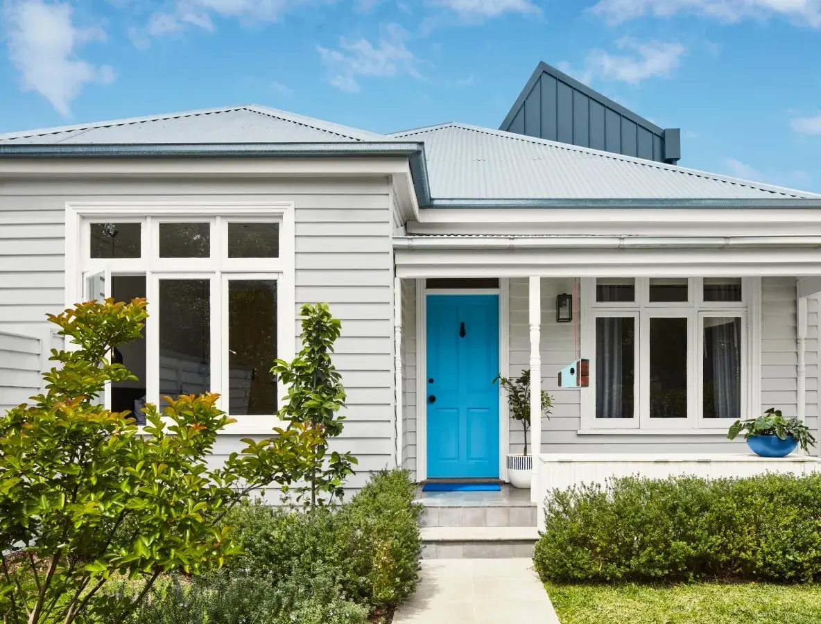 A grey traditional looking house with white trims and a blue front door