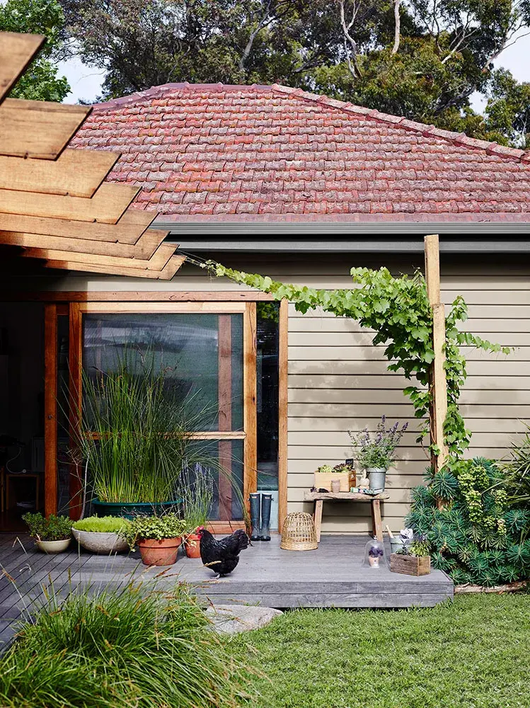 House with teracotta tiled roof and a deck with a black chicken on it