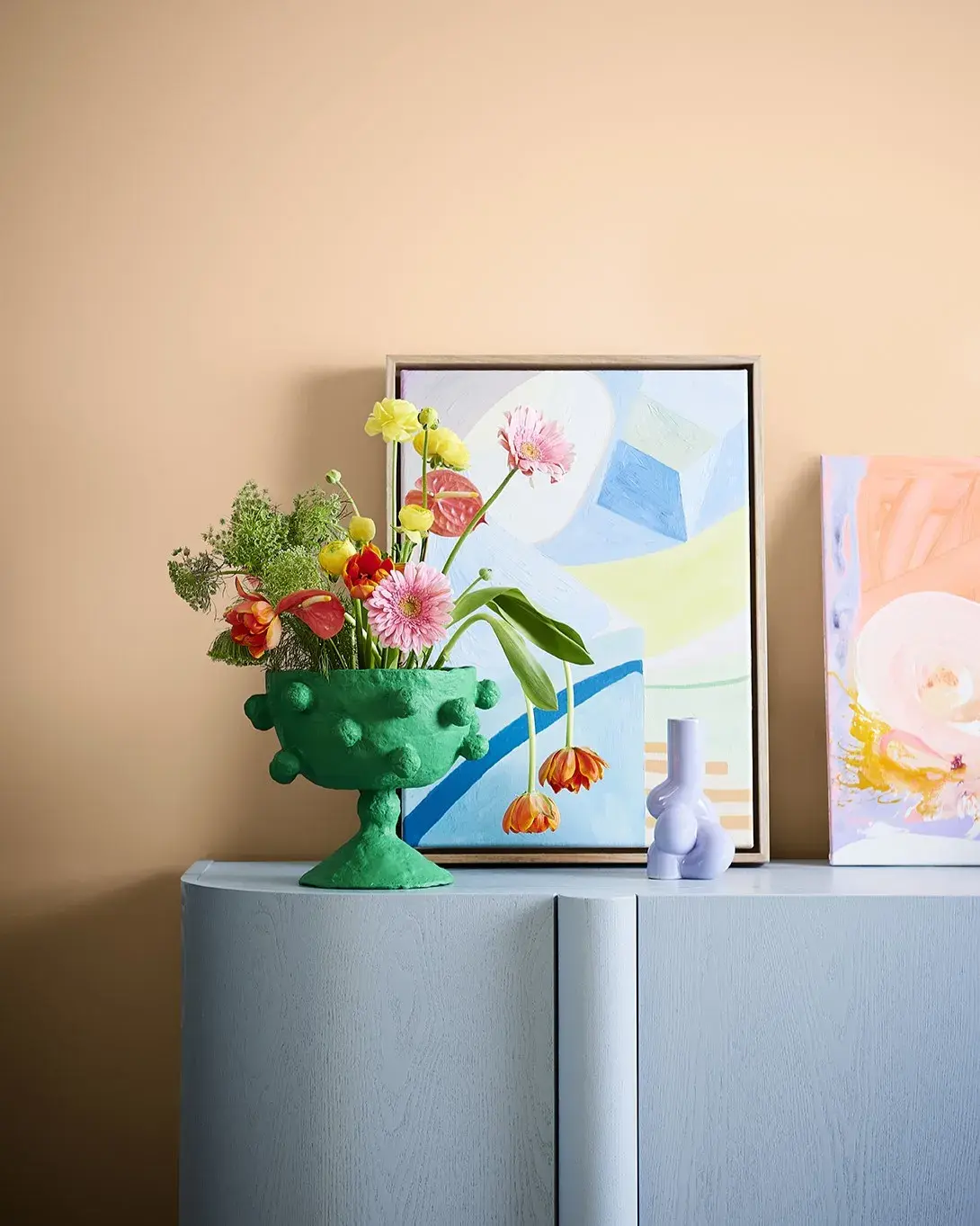Blue console with apricot coloured wall and artwork