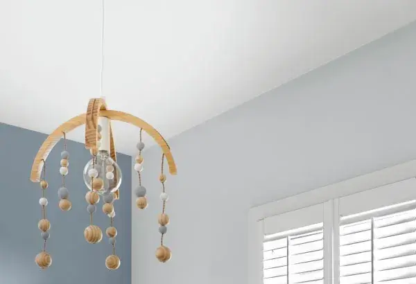A nursery ceiling with a wooden children's dial hanging from it. The walls are blue