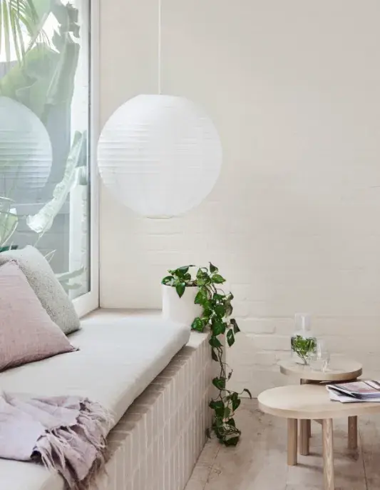 A tiled bench seat with cushion within a white Japandi living room