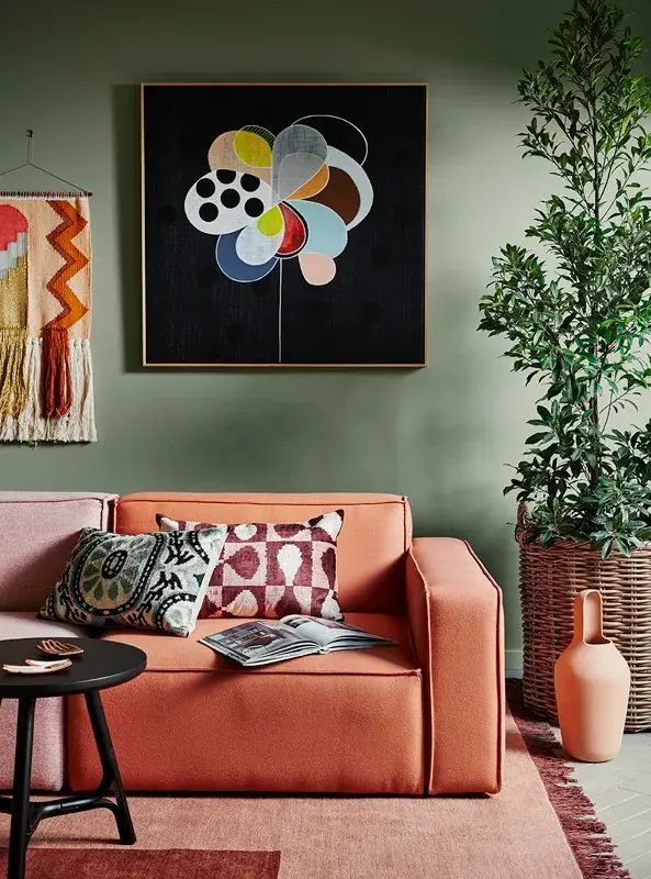 interior green lounge room with orange couch and painting.