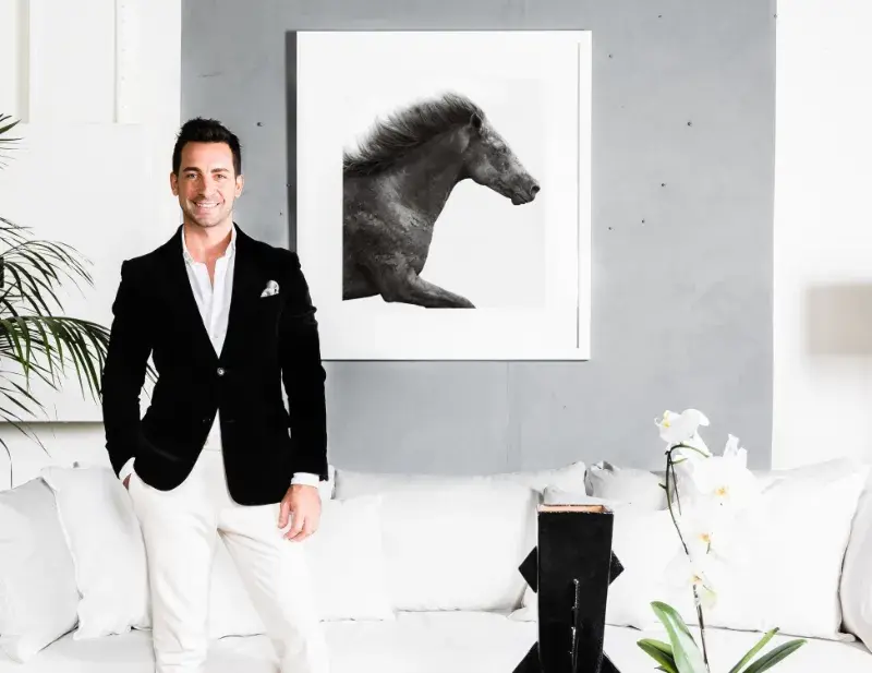 Interior designer Steve Cordony in living area in front of concrete-style wall with photograph of black horse.