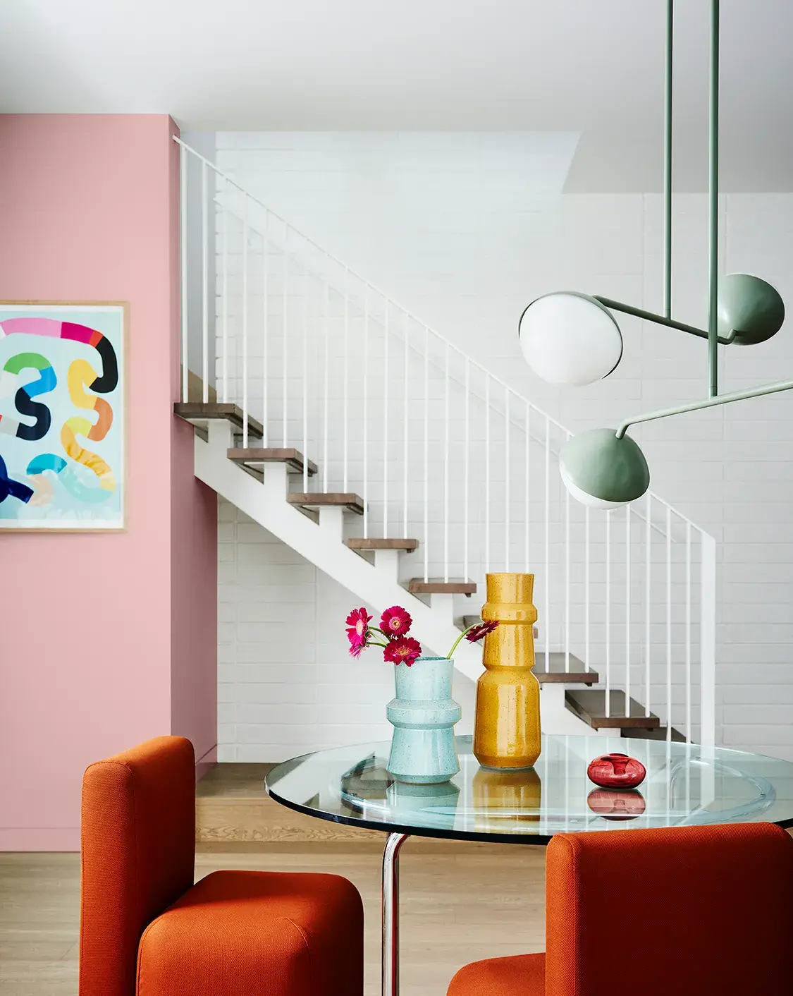 Dining room with view of pink feature wall and white stairs