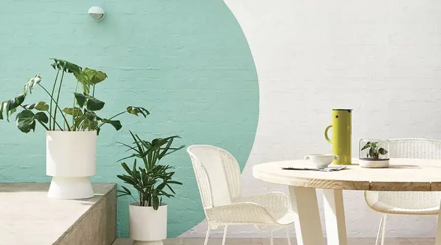 White brick wall with green circle painted on it behind a dining table and plants