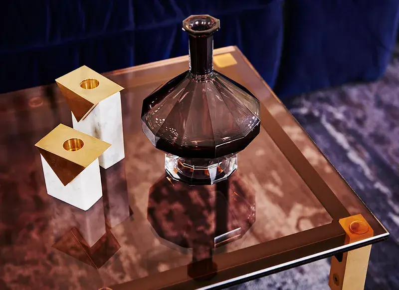Colour Forecast 2018 - Reflect. Living area in plush colours, glass side table, gold candleholders and purple glass decanter