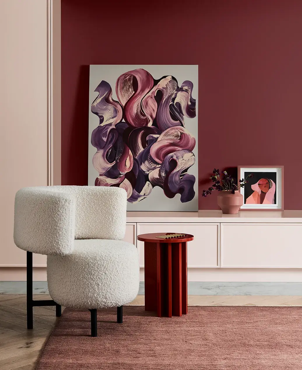 Furry white chair and small side table on rug painting decorations in background on cabinetry.