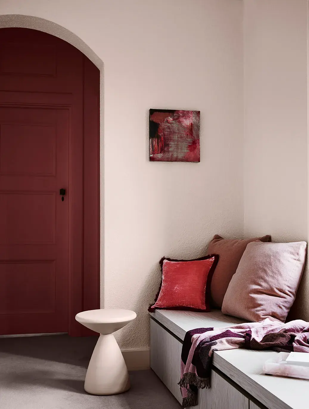 Textured wall with arched doorway. Benchseat with pillows on it. 