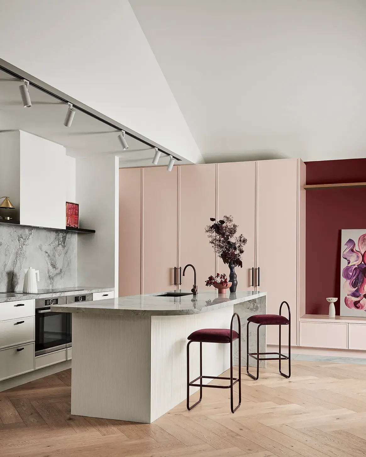 Kitchen with marble benchtops, two bar stools feature at the bench with vases of flours on the bench.