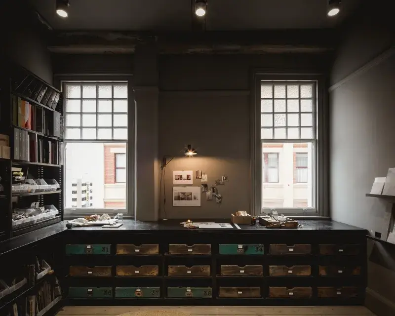 Grey-brown office with low drawers and two windows.