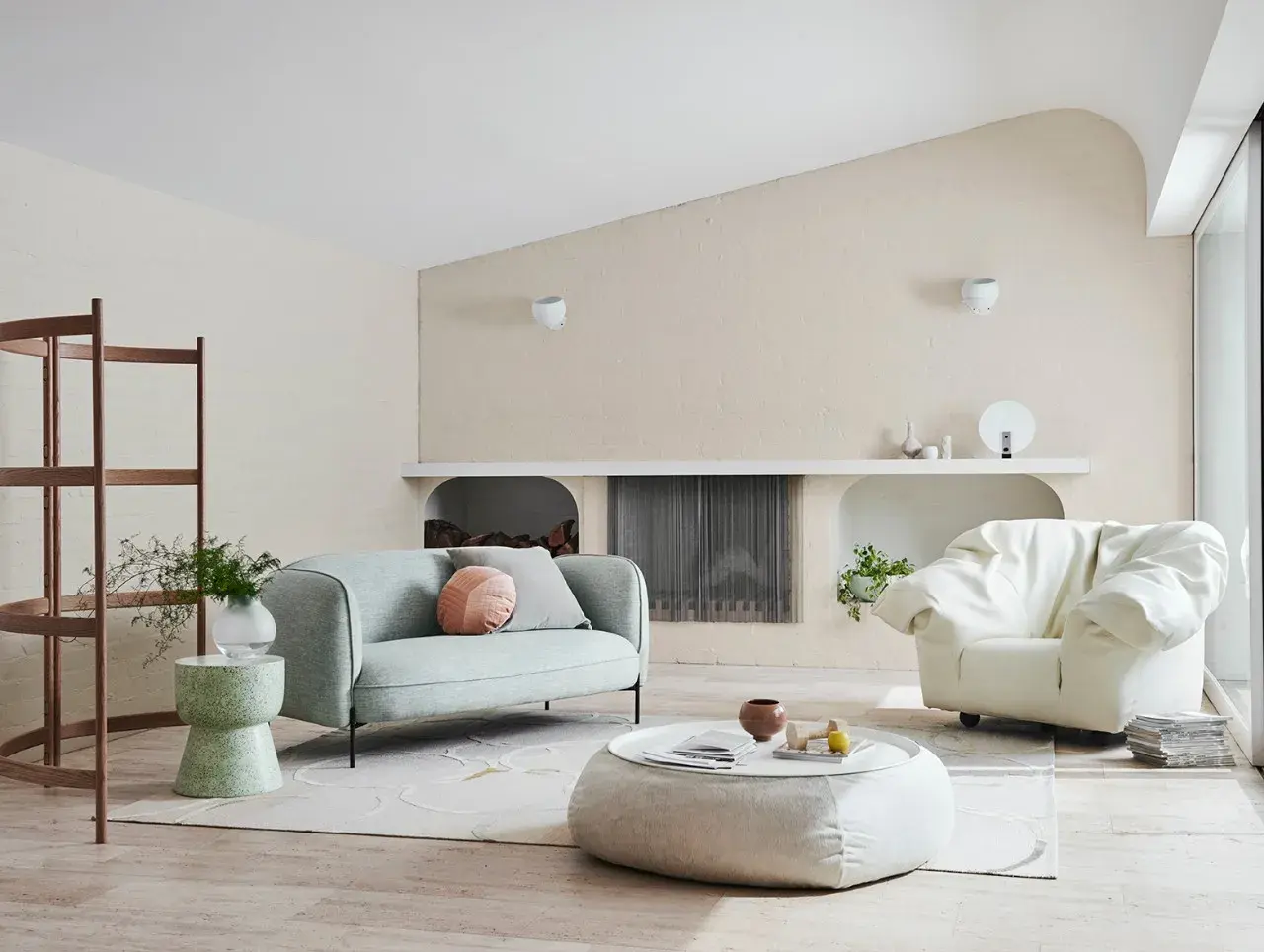 Couch in front of stacked wood for fireplace. Stone side table with vase sitting next to it.